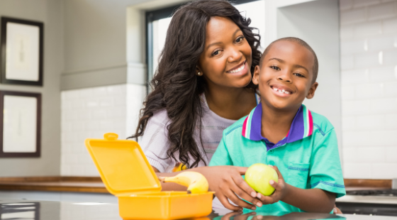 Mother and son preparing lunchbox in kitchen